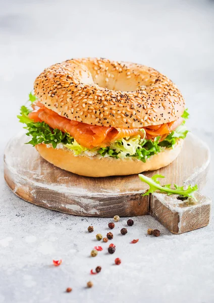 Friss egészséges bagel szendvics lazac, ricotta és saláta vintage aprítódeszka fehér konyhaasztal háttér. Egészséges diétás kaja. Paprika oldalt. — Stock Fotó