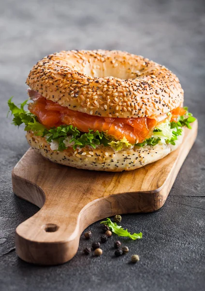 Sanduíche de bagel saudável fresco com salmão, ricota e alface na tábua de corte vintage em fundo de mesa de cozinha de pedra. Alimentação saudável . — Fotografia de Stock