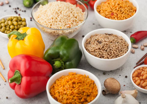 White bowl plates with boiled long grain basmati rice with vegetables and mushrooms on light table background with sticks and paprika pepper with corn,garlic and basil. Healthy vegan food. — Stock Photo, Image