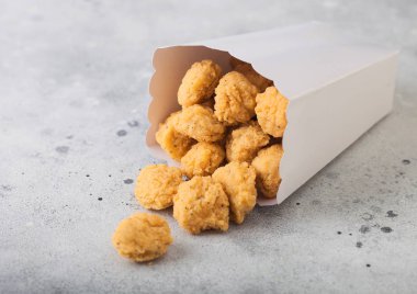Kıtır kıtır güney tavuk patlamış mısırı hafif arka plandaki fast food yemekleri için beyaz kağıt kutusunda ısırıyor.. 