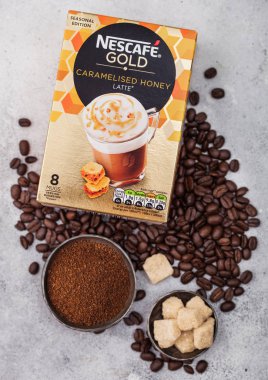 Londra, Uk - 15 Ağustos 2019: Hafif mutfak arka planında kahve çekirdekleri ve şeker küpleriyle bir paket Nescafe Gold Karamel Bal Latte. 