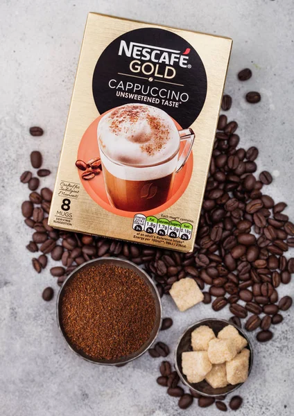 LONDRES, Reino Unido - 15 de agosto de 2019: Pack de Nescafe Gold Cappuccino sabor sin azúcar con granos de café y terrones de azúcar sobre fondo de cocina claro . —  Fotos de Stock