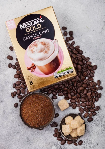 LONDRES, Reino Unido - 15 de agosto de 2019: Pack de Nescafe Gold Cappuccino flaco con granos de café y terrones de azúcar sobre fondo de cocina claro . —  Fotos de Stock