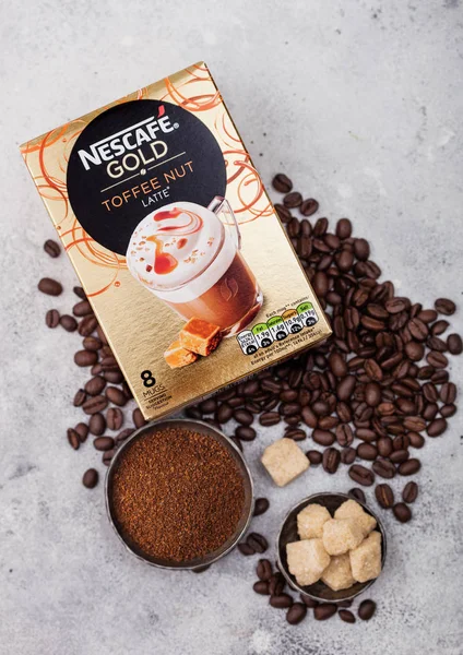 LONDRES, Reino Unido - 15 de agosto de 2019: Pack de Nescafe Gold Toffee Nut Latte con granos de café y terrones de azúcar sobre fondo de cocina claro . —  Fotos de Stock