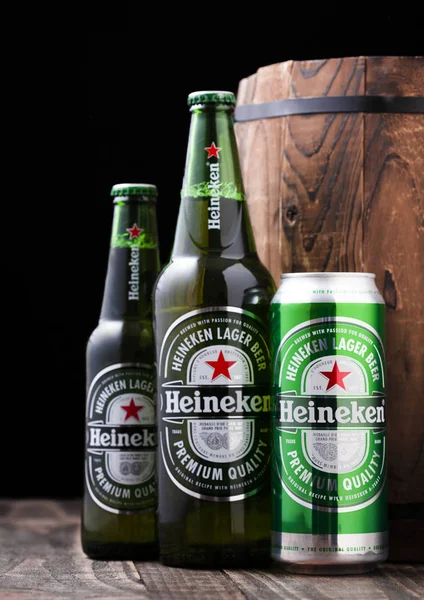 LONDRES, Reino Unido - 27 DE ABRIL DE 2018: Botellas y latas de aluminio de cerveza Heineken Lager Cerveza junto al barril de madera . — Foto de Stock