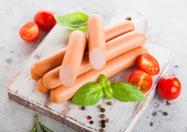 Klassische gekochte Schweinswürste auf Schneidebrett mit Paprika und Basilikum und Kirschtomaten auf hellem Hintergrund. Ansicht von oben — Stockfoto