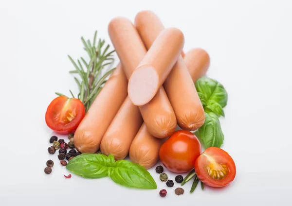 Klassische gekochte Schweinswürste mit Paprika und Basilikum und Kirschtomaten auf weißem Hintergrund. Makro — Stockfoto