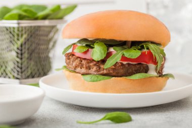 Sağlıklı vejetaryen etsiz burger. Yuvarlak seramik tabakta sebzeler ve arka planda ıspanak..