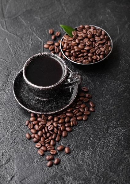 Cup of fresh raw organic coffee with beans and coffee tree leaf on black background. Top view. — Stock Photo, Image