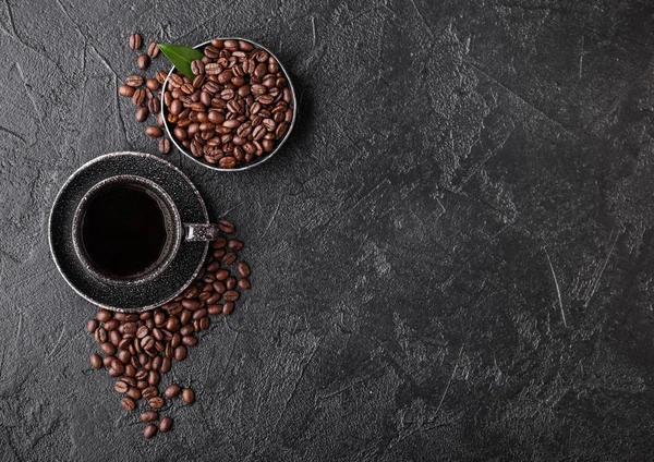 Filiżanka świeżej kawy organicznej z fasolą i liściem drzewa kawowego na czarnym tle. Widok góry. Miejsce na tekst — Zdjęcie stockowe