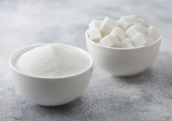 Białe talerze miski naturalnych kostek cukru białego i cukru rafinowanego na jasnym tle stołu. — Zdjęcie stockowe