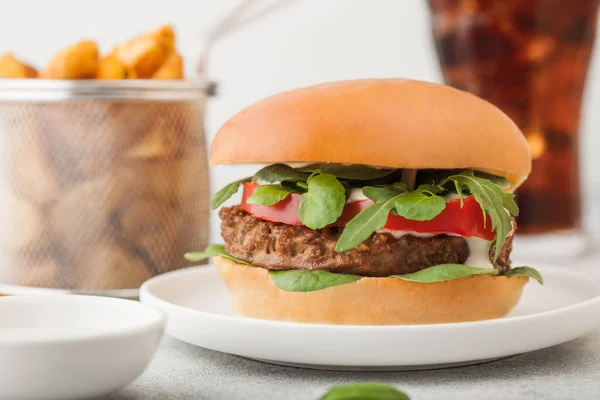 Healthy vegetarian meat free burger on round ceramic plate with vegetables on light table background with potato wedges and glass of cola. — Stock Photo, Image