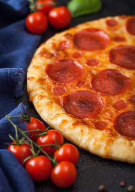 Siyah arka planda fesleğenli domatesli taze pişmiş Pepperoni İtalyan pizzası. Üst görünüm