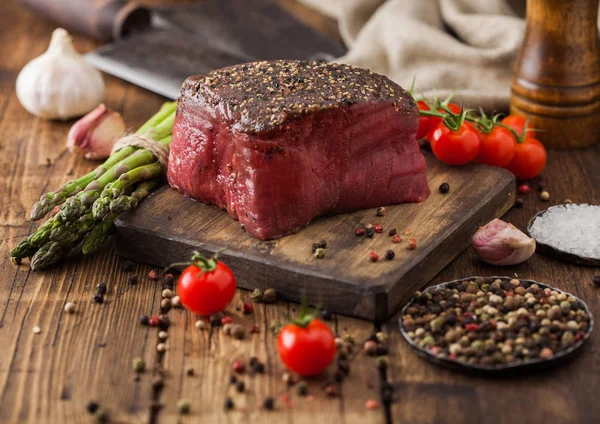 Skiva rått nötkött ovansida fog med salt och peppar på trä hackbräda med tomater vitlök och sparris tips. — Stockfoto