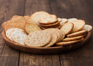 Çeşitli organik buğday, çavdar ve mısır gevreği. Tahta zemin üzerinde susamlı ve tuzlu krakerler..