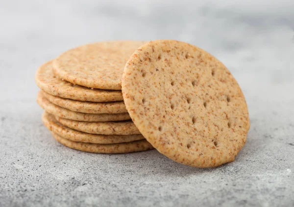 Stack of various organic crispy wheat crackers with sesame and salt on light kitchen table background. — Stock Photo, Image