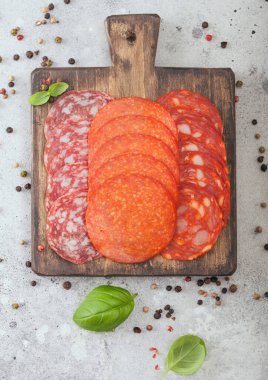 Kurutulmuş sucuklu sucuk dilimleri ve fesleğenli salam ve ahşap doğrama tahtasında ve arka planda hafif karabiber.. 