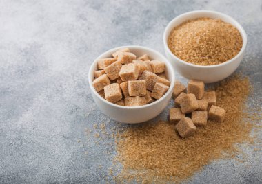 Beyaz kase tabakları, doğal kahverengi şeker küpleri ve hafif arkaplanda rafine edilmiş şeker.. 