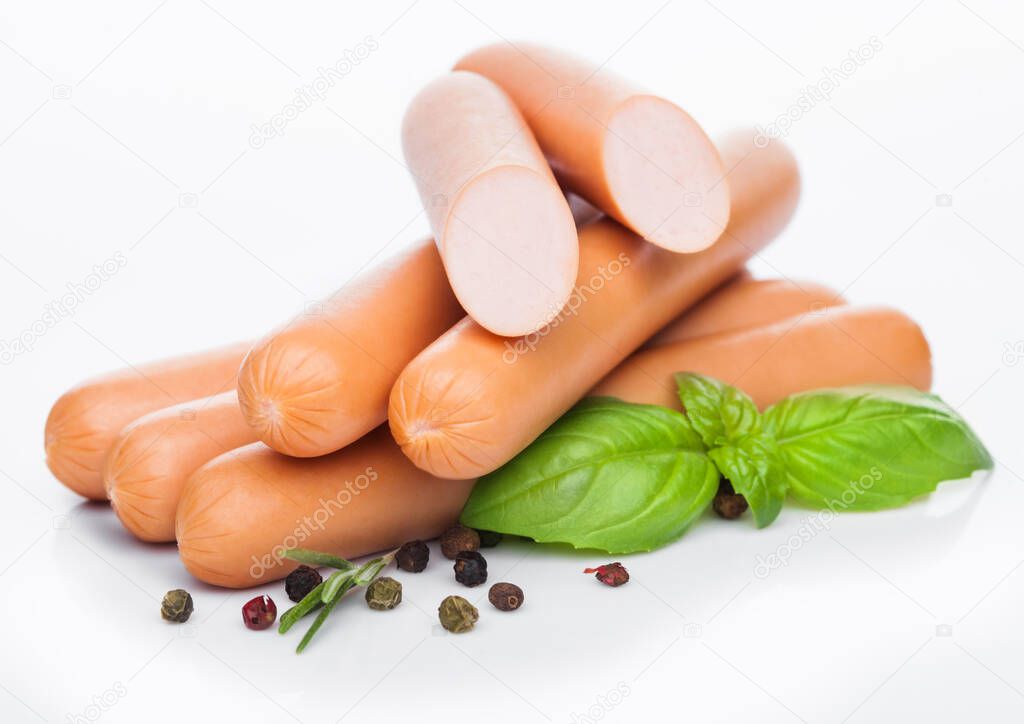 Classic boiled meat pork sausages with pepper and basil on white.