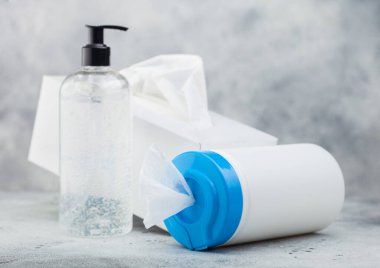 Beyaz arka planda plastik mendiller, el dezenfektanı plastik kaplar ve bir kutu mendil. Tüm virüslerden en iyi korunma.