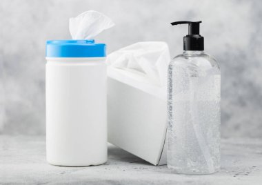 Beyaz arka planda plastik mendiller, el dezenfektanı plastik kaplar ve bir kutu mendil. Tüm virüslerden en iyi korunma.