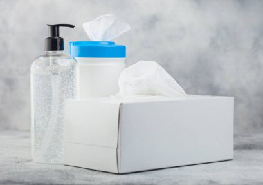 Beyaz arka planda plastik mendiller, el dezenfektanı plastik kaplar ve bir kutu mendil. Tüm virüslerden en iyi korunma.