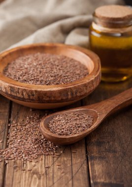 Tahta kasede doğal organik keten tohumu ve ahşap arka planda kaşık ve yağ. Sağlıklı Omega 3 ürünü.