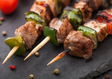 Izgara domuz eti ve kırmızı biberli tavuk kebabı. Tuz, biber ve domatesli taş doğrama tahtası. Makro