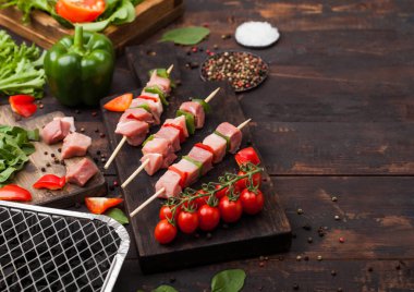 Kırmızı biberli çiğ domuz kebabı taze sebzeler ve ahşap arka planda tek kullanımlık kömür ızgarası. Marul ve kırmızı biberli tuz ve biber..