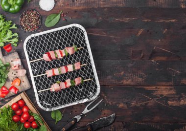 Çiğ domuz kebabı, tek kullanımlık kömür ızgarasında kırmızı biber, ahşap arka planda taze sebze çatal ve bıçakla birlikte. Marul ve kırmızı biberli tuz..