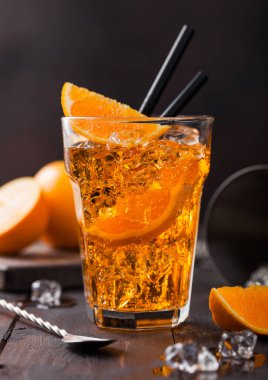 Aperol spritz yaz kokteyli. Viski bardağında portakal dilimleri ve siyah arka planda buz küplü bar kaşığı. Iace küpleri ve süzgeçli kokteyl sallayıcısı