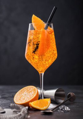 Portakal dilimli aperol spreyli yaz kokteyli ve siyah arka planda buz küplü jigger..