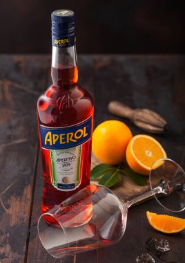 LONDON, İngiltere - 20 Mayıs 2020: Ahşap arka planda boş cam ve portakallı bir şişe Aperol Aperitivo yaz kokteyli.