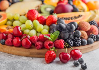 Taze çiğ organik yaz meyveleri ve egzotik meyveler mutfak arka planında geniş tepside. Papaya, üzüm, nektarin, portakal, ahududu, kivi, çilek, liçi, kiraz. Üst görünüm