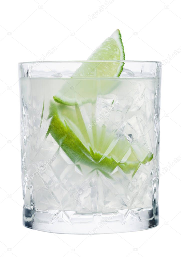 Gimlet cocktail in crystal glass with ice cubes and lime slices isolated on white background.