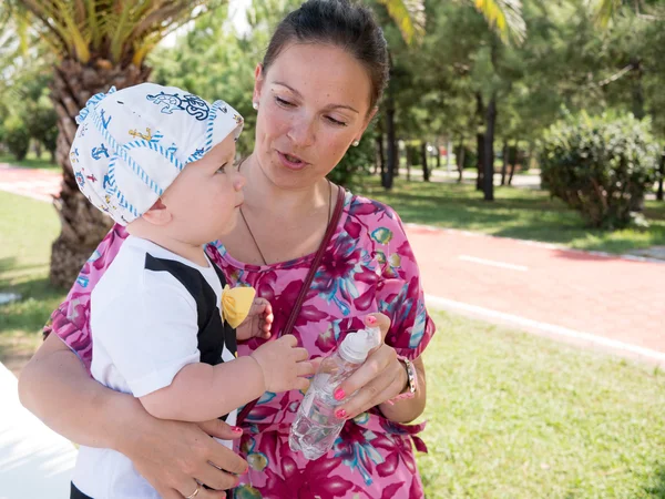 Mutlu anne tatil tropikal Maldivler üzerinde sahip şirin bebek çocuk ile. Palmiye ağaçları arasında oynayan çocuk