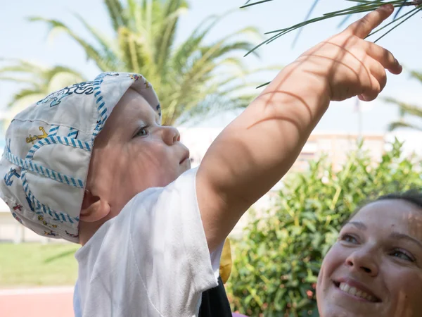 Mutlu anne tatil tropikal Maldivler üzerinde sahip şirin bebek çocuk ile. Palmiye ağaçları arasında oynayan çocuk