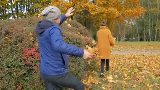 Baba ile kızı sonbahar parkta oynarken. Ancak, gülümse ve gülmek. Baba atar yaprakları bir gencin kafasına. — Stok video