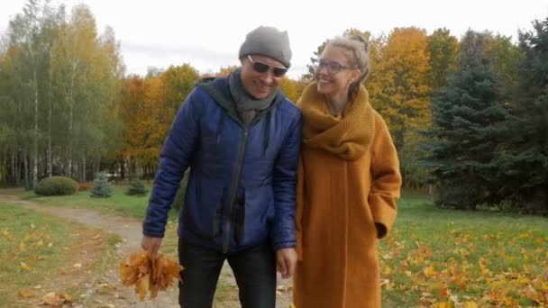 Padre che cammina con la figlia nel parco in autunno. Papà e adolescente sorridono e ridono e giocano con un bel fogliame giallo — Video Stock