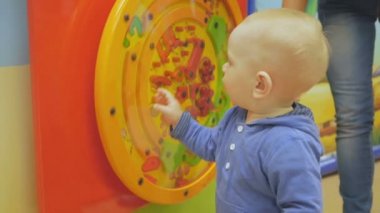 Bir çocuk büyük bir alışveriş merkezi Eğlence Merkezi'nde oynuyor. Birçok ilginç eğitim oyunları bebek çekmek.
