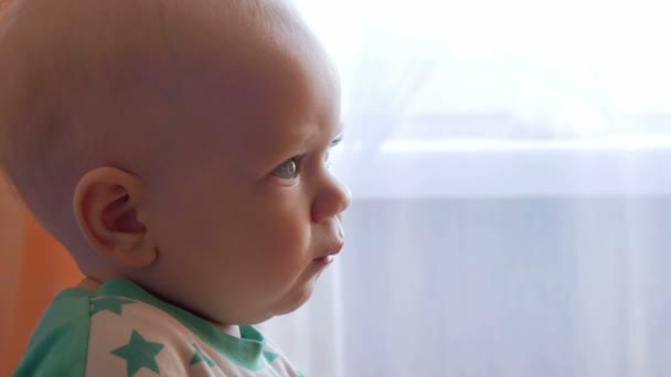 Maman nourrit le beau bébé avec une bouillie de fruits cuillère. L'enfant regarde attentivement un point. Gros plan — Video