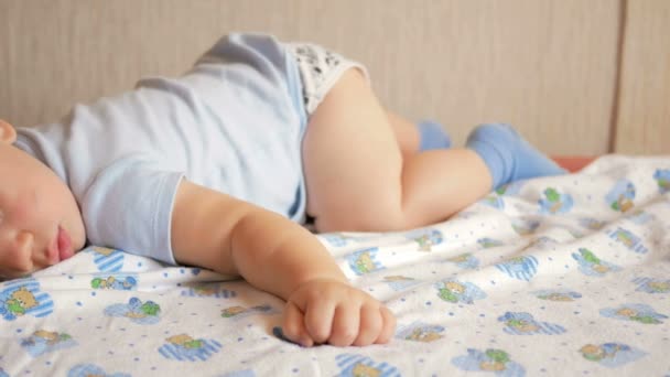 Schönes Baby, das in lustiger Pose auf einem Bett schläft. unter der Babywindel, der Junge etwa ein Jahr — Stockvideo