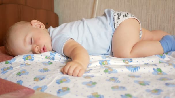 Bebê bonito dormindo em pose engraçada em uma cama. Sob a fralda de bebê, o menino cerca de um ano — Vídeo de Stock