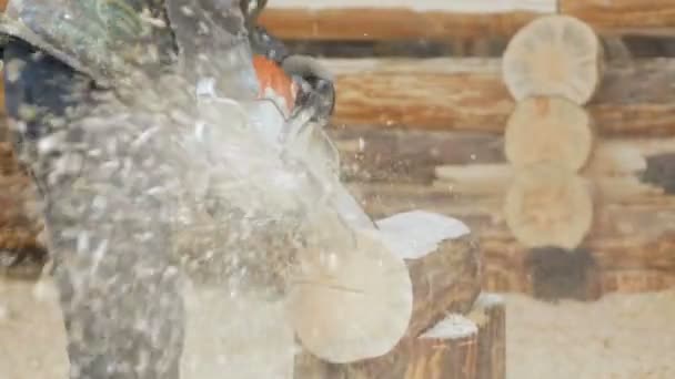 Bauarbeiter greift zur Holzkettensäge. vor dem Hintergrund ist Teil der Zukunft des Hauses aus Holzbalken, Zeitlupe — Stockvideo