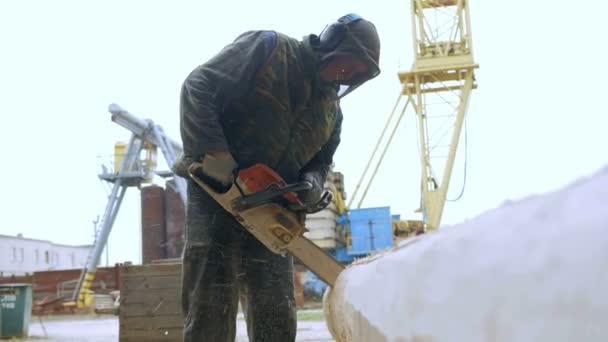 Člověk dělá složené řezání dřeva motorovou pilou. Protokol bude součástí budoucnosti dřevěného domu. Ochranná maska na přední straně builder a spousta pilin. — Stock video