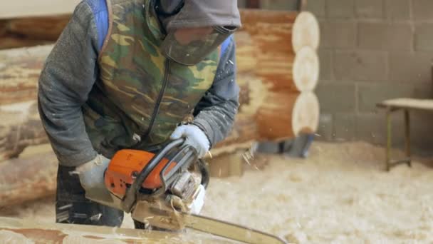 L'homme fait de la tronçonneuse. Le rondin fera partie de l'avenir de la maison en bois. Masque protecteur sur le visage du constructeur et beaucoup de sciure de bois . — Video
