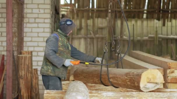 Costruttore solleva legname di legno con Overhead Winch Crane. Un uomo tiene un tronco e lo trasferisce nella futura casa. — Video Stock