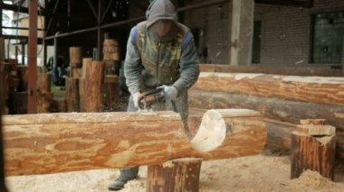Adam ahşap testere gelecekteki ev için keser. Builder ve bir sürü talaş yüzünde koruyucu yüz maskesi. Hangar gelecekteki ev arka planda bir bölümüyle