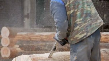Adam ahşap testere gelecekteki ev için keser. Builder ve bir sürü talaş yüzünde koruyucu yüz maskesi. Hangar gelecekteki ev arka planda bir bölümüyle