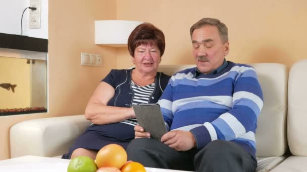 Boldog idősebb férfi és nő beszél a tablet Pc otthon a gyerekekkel. Video hívás az interneten keresztül segít, hogy beszéljen a rokonok. Férj és feleség egy gyönyörű házban — Stock videók
